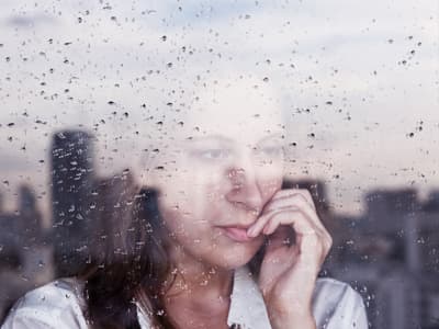 concept of woman with schizophrenia looks out window with reflection of city